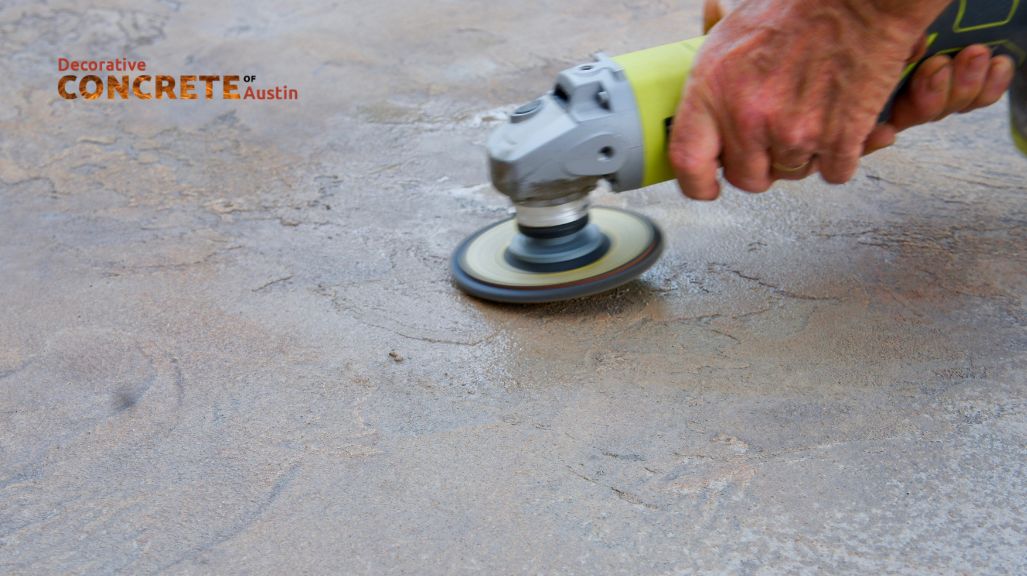 Hands using an electric sander smooth rough concrete, showcasing a polished texture.