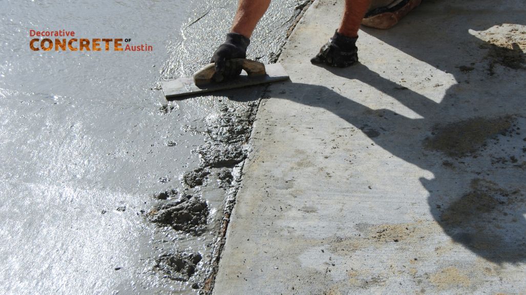 Worker smoothing wet concrete with a trowel on a sunny day, displaying skill and precision.
