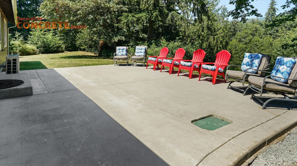 Spacious concrete patio with red Adirondack chairs and cushioned loungers