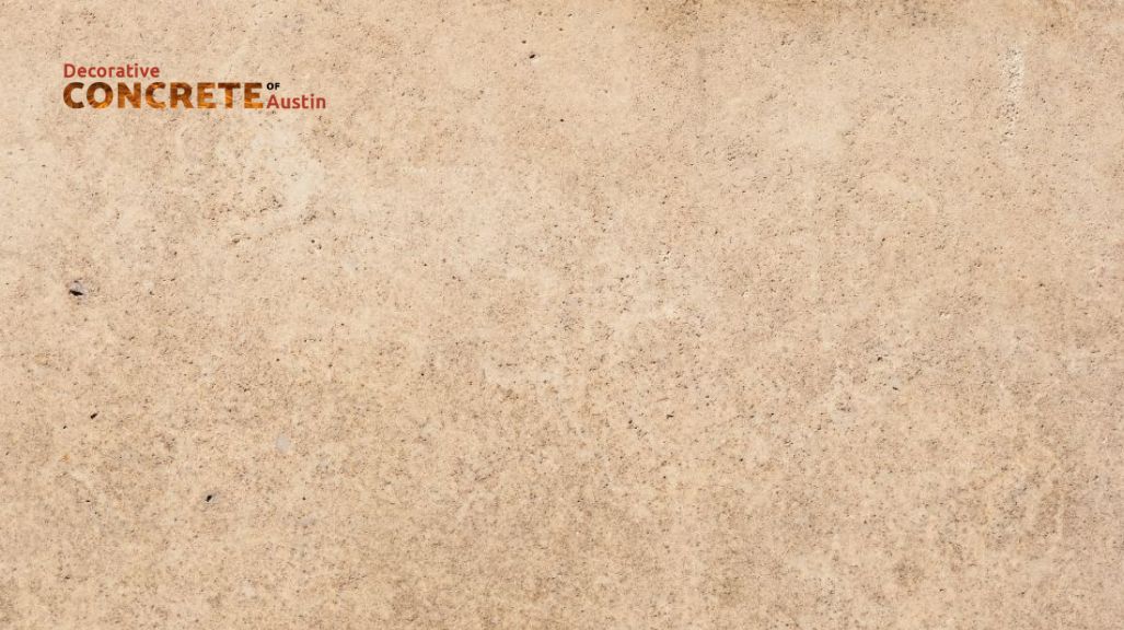 Rough beige textured concrete surface with a logo reading "Decorative Concrete of Austin" in the top left corner, projecting a rustic tone