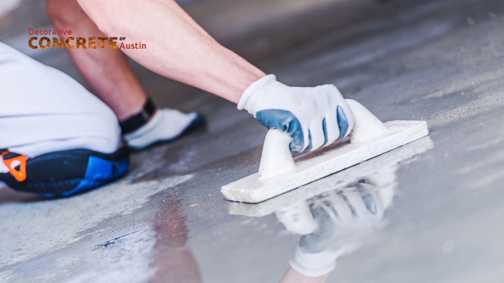 A person smooths wet concrete with a trowel, wearing white gloves