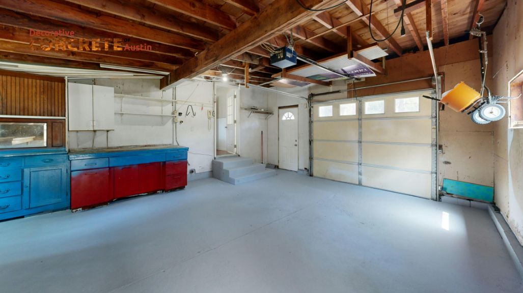 A spacious, empty garage with a concrete floor, exposed wooden beams, and a large garage door. 