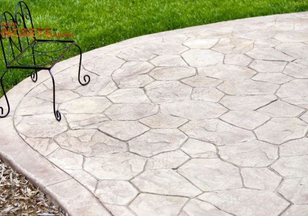 Stamped concrete patio with a hexagonal pattern, bordered by green grass.